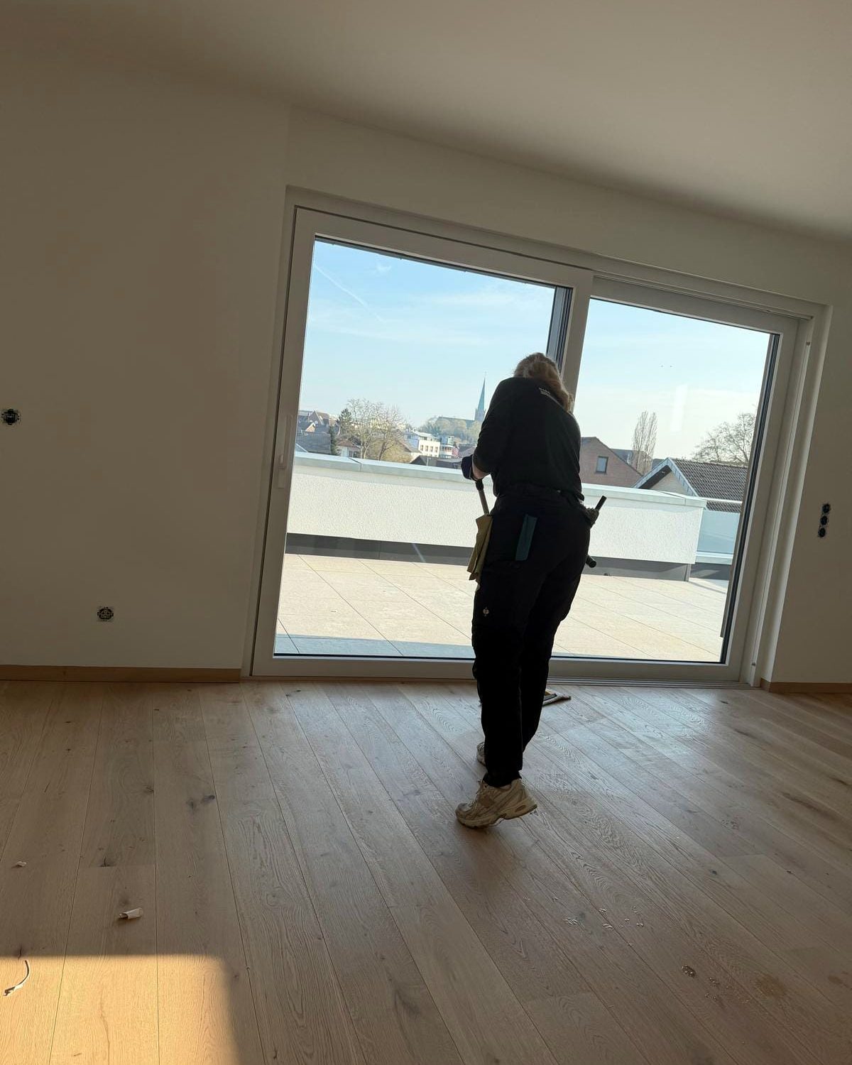 Mitarbeiterin von Gashi Immobilienservice bei der Fensterreinigung einer bodentiefen Fensterfront in einem Neubau